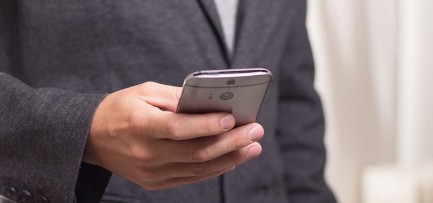 hand of man in suit holding smartphone