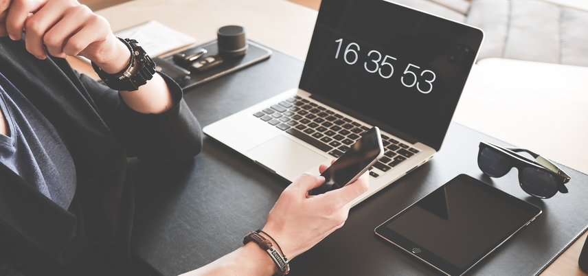 hand holding smart phone next to laptop