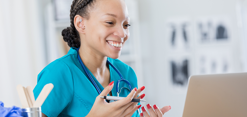 Healthcare worker taking video call on laptop.