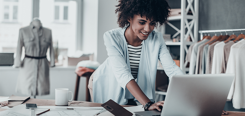 Woman working on laptop in retail environment.