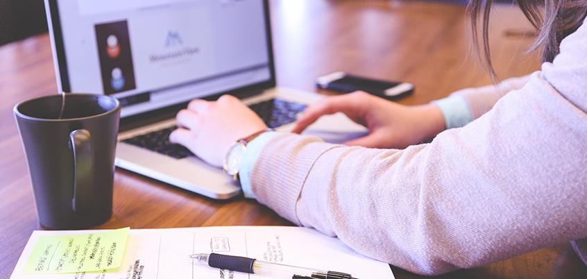 Photo of person working on laptop at desk.