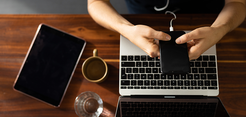 Overhead photo of person on phone in front of laptop.