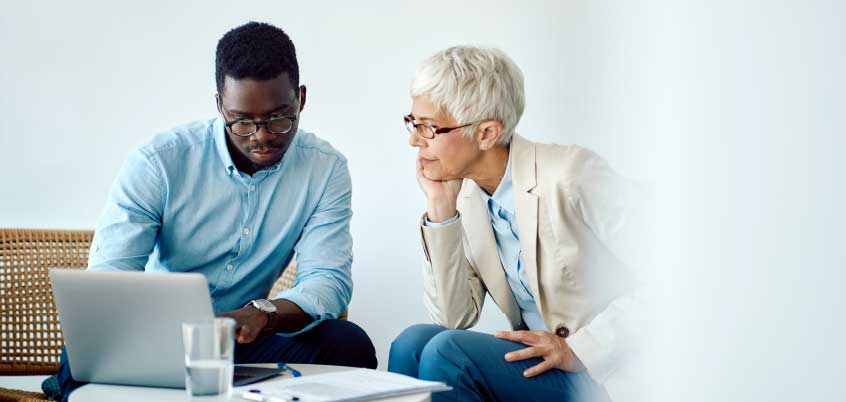 Man and woman sitting at table looking at laptop