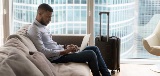 man sitting on couch in hotel room using laptop