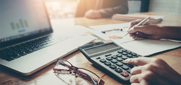 tax-tips-featured-image-03 Person working at desk with laptop and calculator