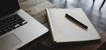 website-project-plan-hero closeup of laptop and notebook on cafe table
