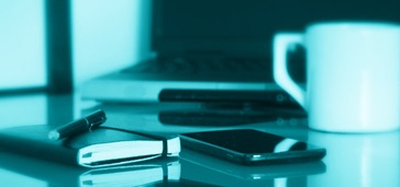 what-mobile-apps--choosing-the-right-type-of-app notebook, smartphone, and coffeecup on table; blue-green tint over entire image