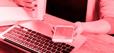 what-mobile-apps--mistakes-to-avoid woman's hands holding smartphone and drink over laptop, pink tint